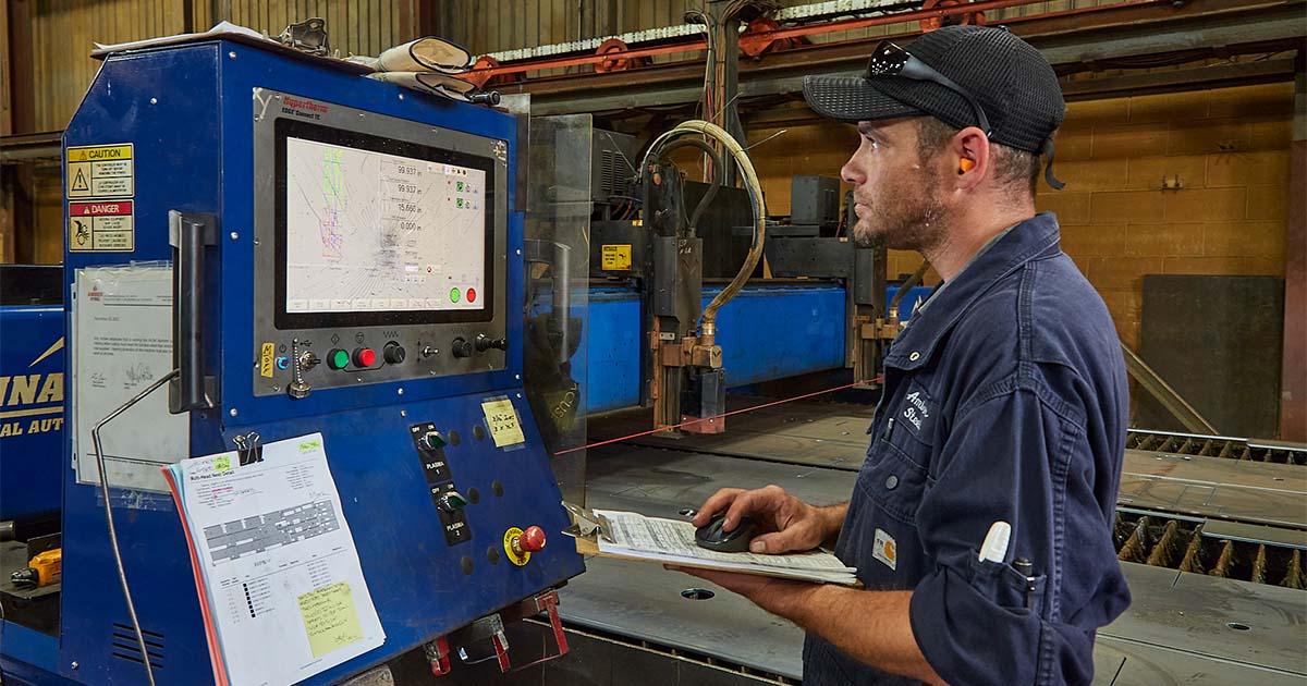 (Operator at control panel): A factory worker operating a CNC control panel, monitoring cutting processes with a focused expression.